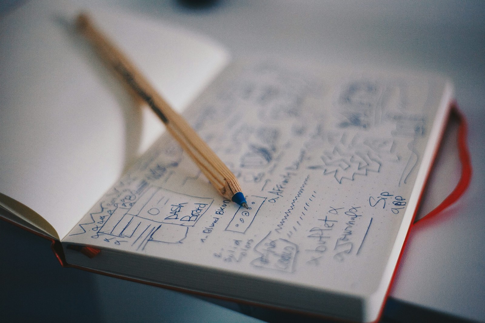 Pen resting on hand-drawn interface wireframes in a notebook