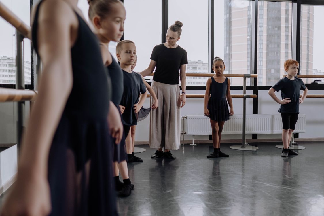 Children learning ballet with their instructor in a bright studio